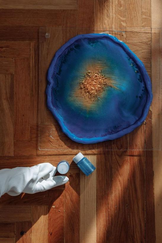 Blue geode resin clock curing on a wooden floor