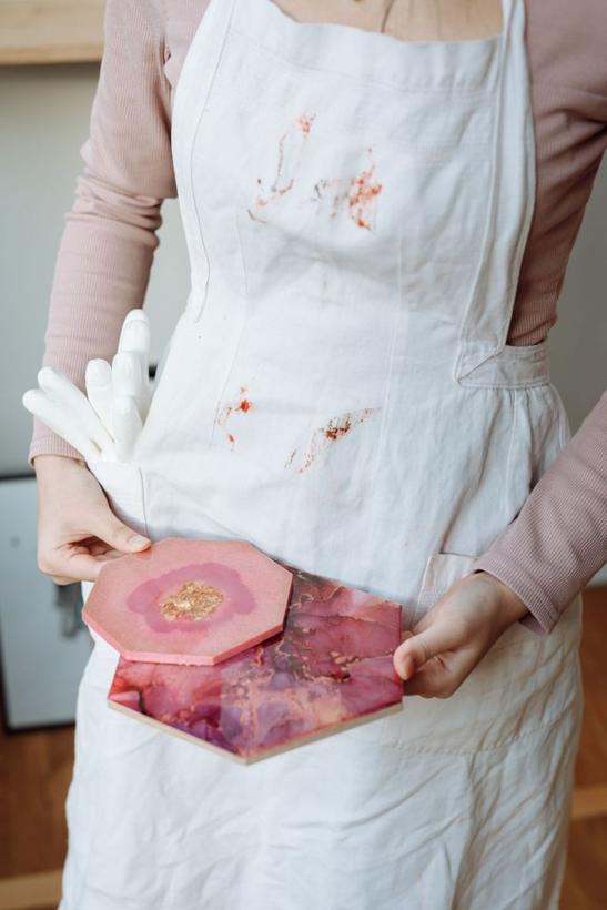 Pink hexagon resin coasters held in an apron